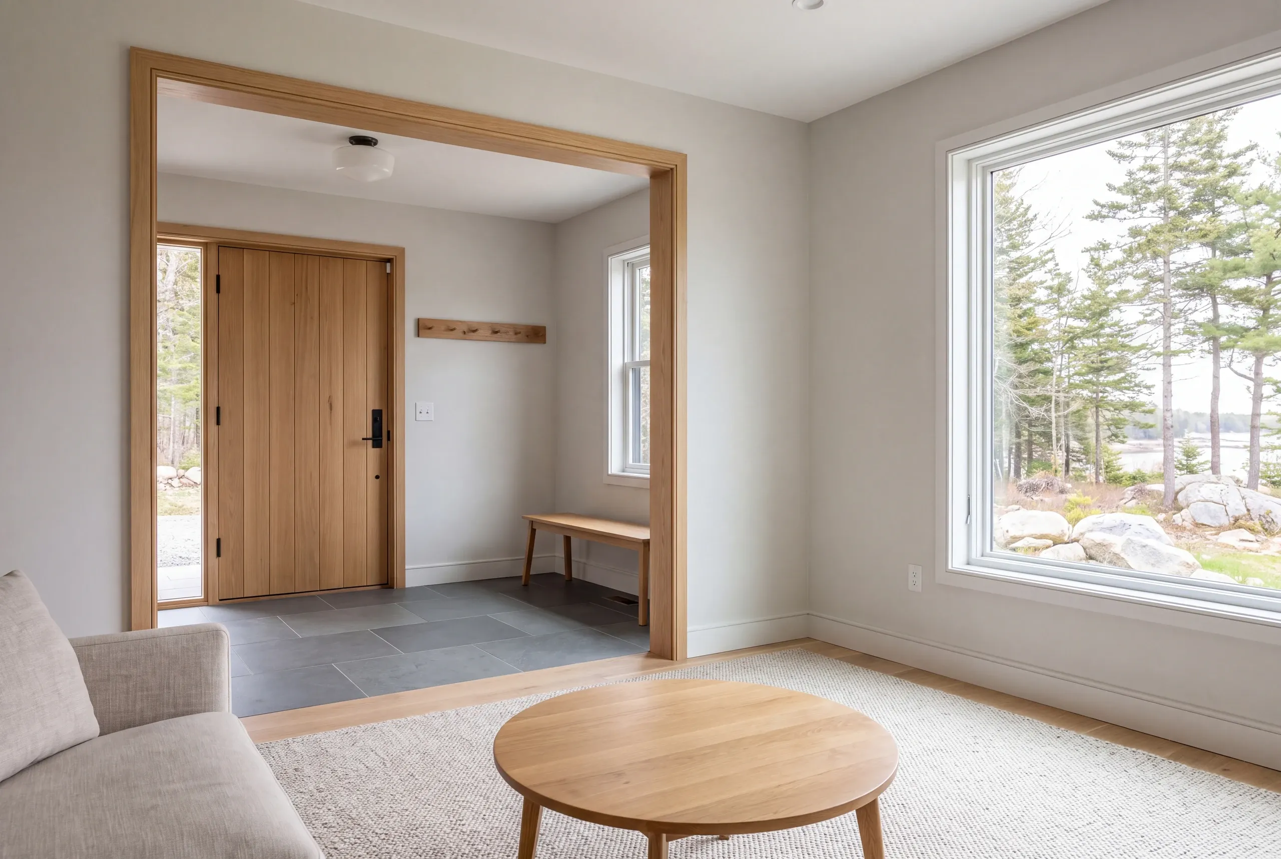 Interior view showing a living space with a round coffee table and a doorway leading into a finished entryway with a wooden front door and tile flooring.