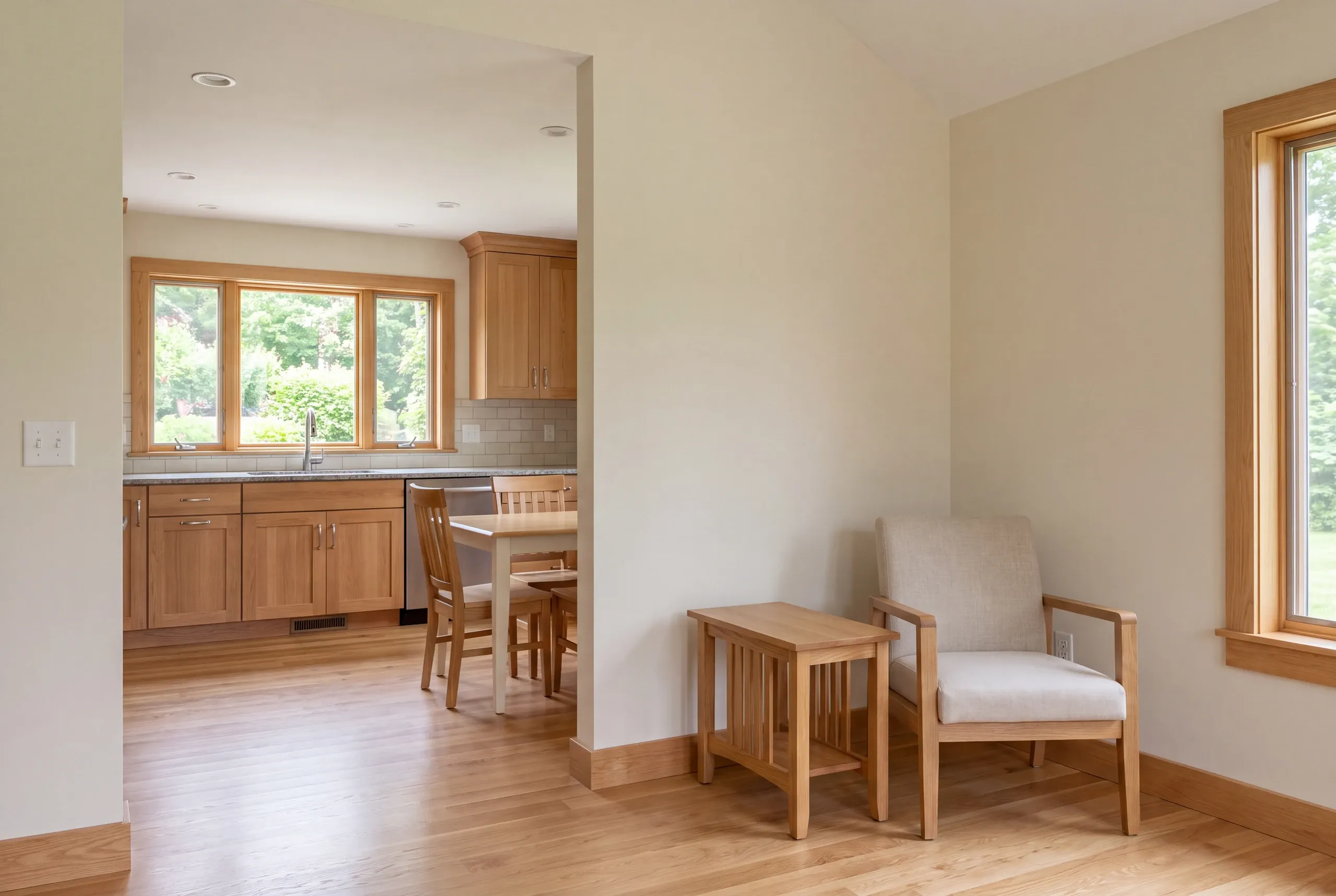 A newly remodeled kitchen opening into a finished living room with light wood floors and trim.