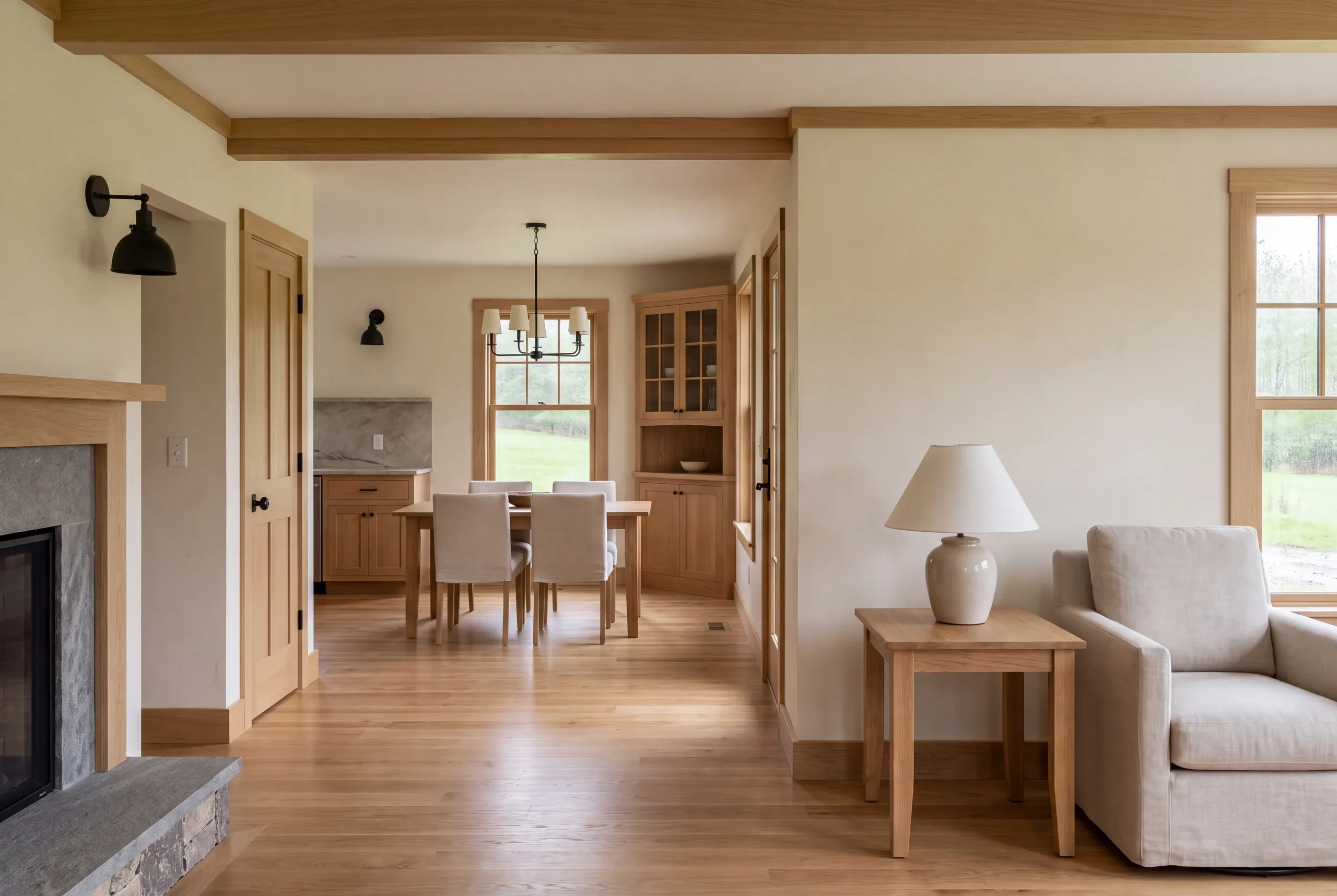 An interior shot shows a living area with a fireplace and armchair in the foreground, leading through an open walking route to a dining space and kitchen in the background.
