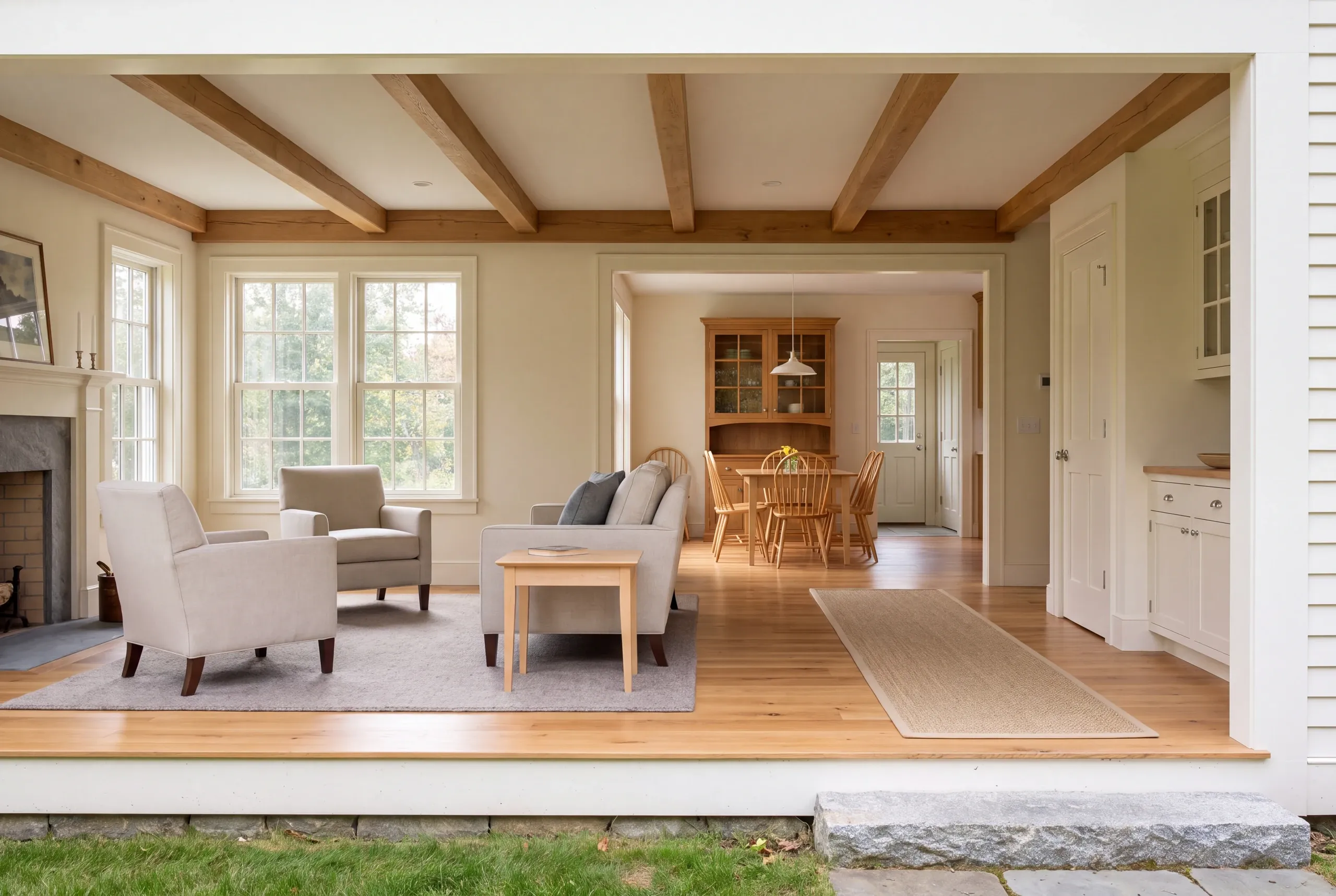 A finished living room with seating, a fireplace, exposed wood ceiling beams, and a view into a dining area.