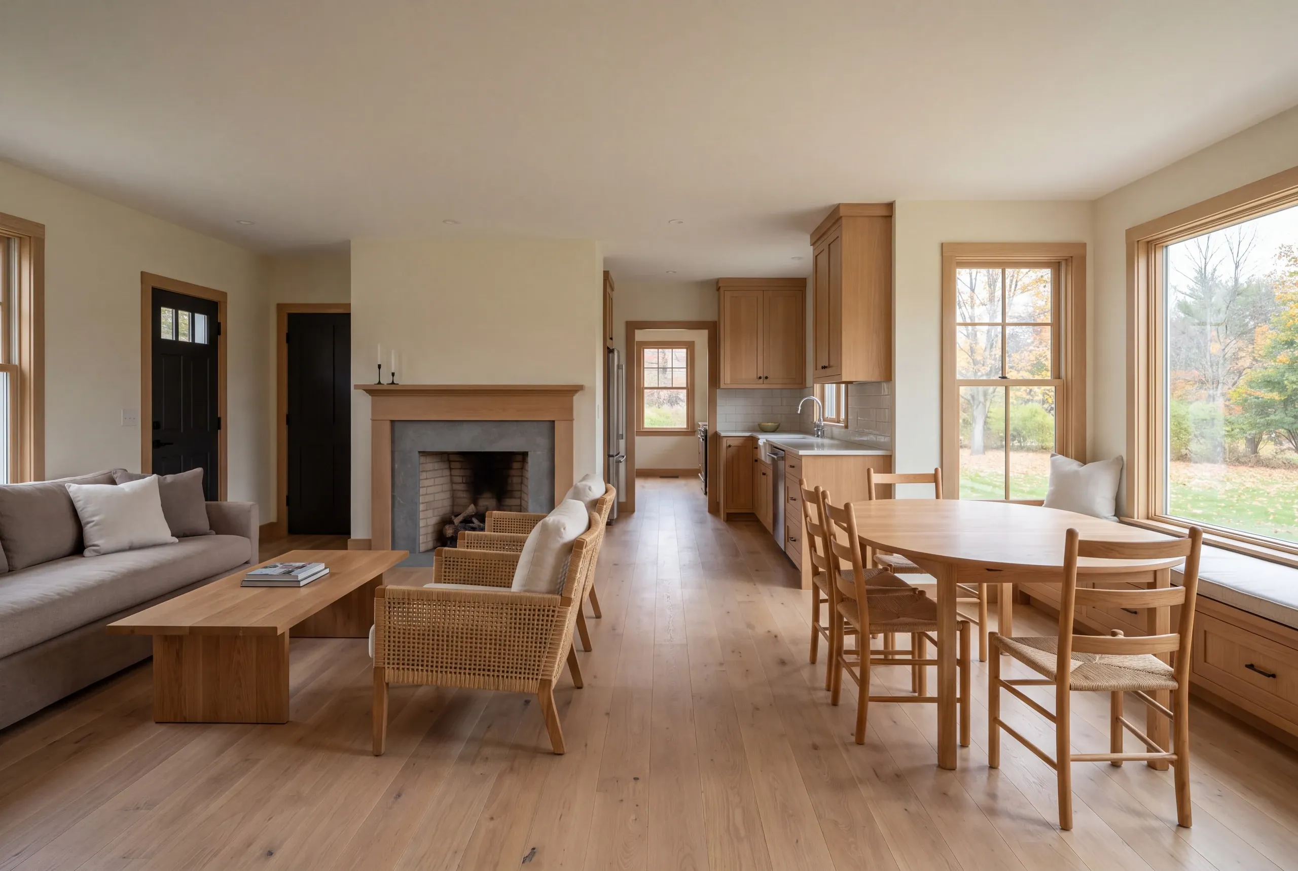 A finished living and dining room with a sofa, fireplace, wooden armchairs, and a dining table with chairs.