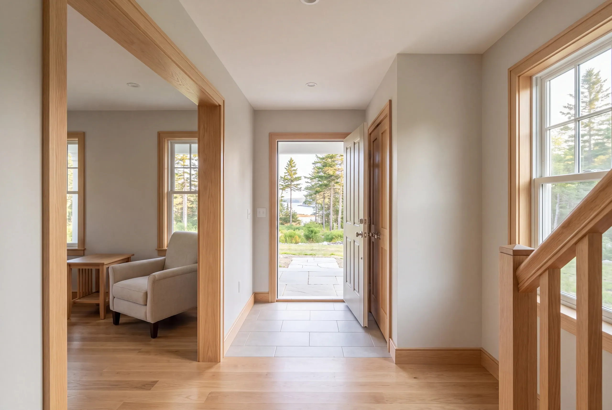 A finished indoor entry hallway featuring wood trim, tile flooring near the open exterior door, and a view into an adjacent living space.