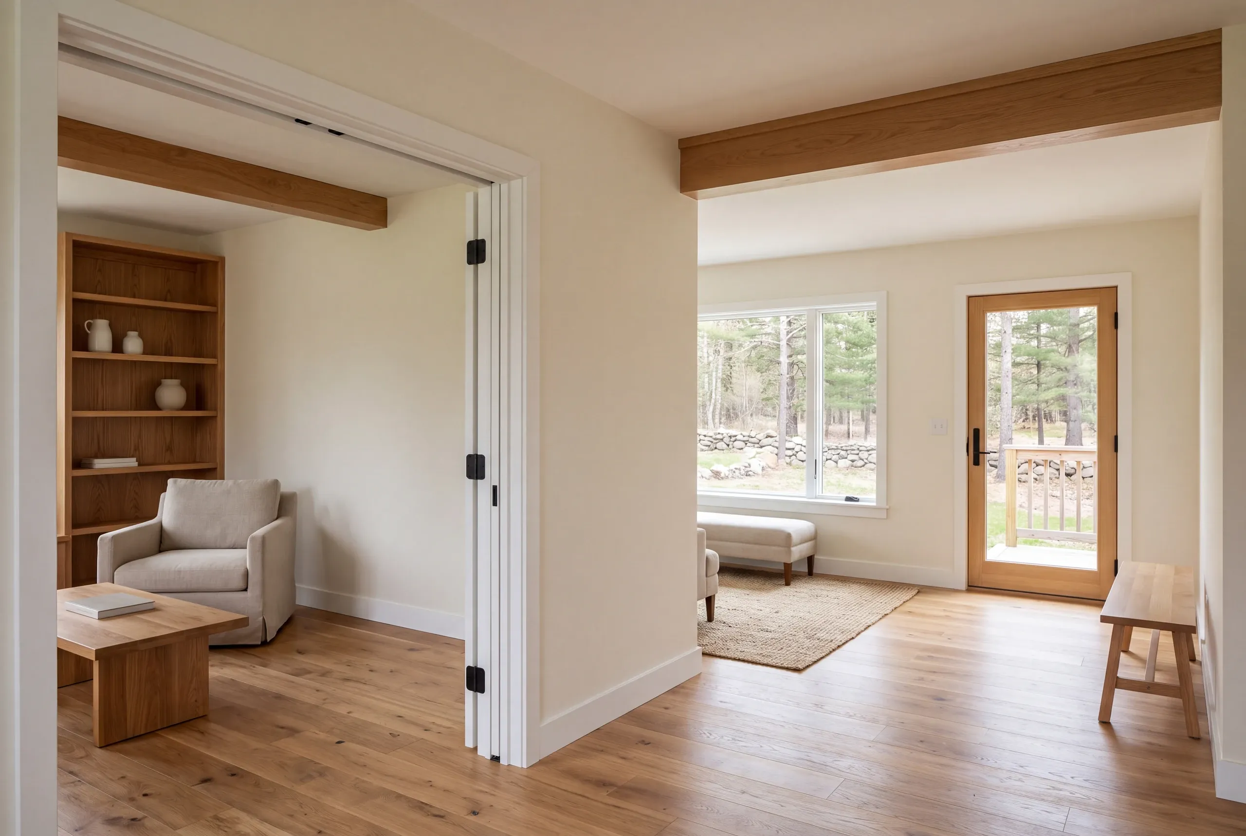 Interior view showing a finished connection between two rooms with wood flooring and exposed ceiling beams.