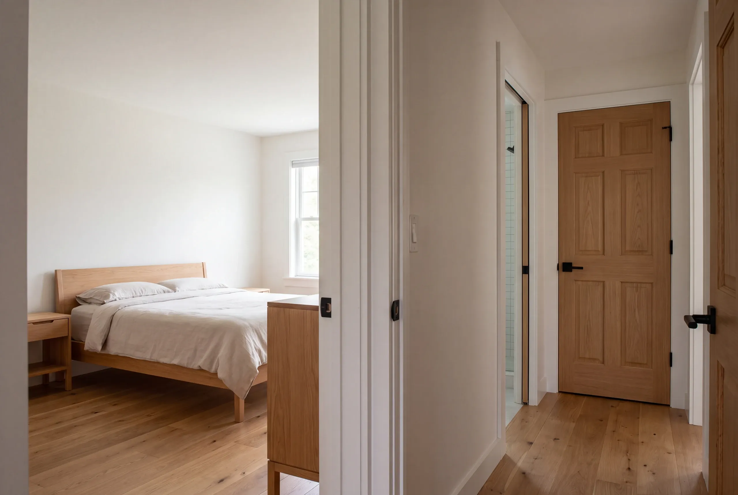 Interior view of a bedroom suite opening to a hallway with a wooden door.