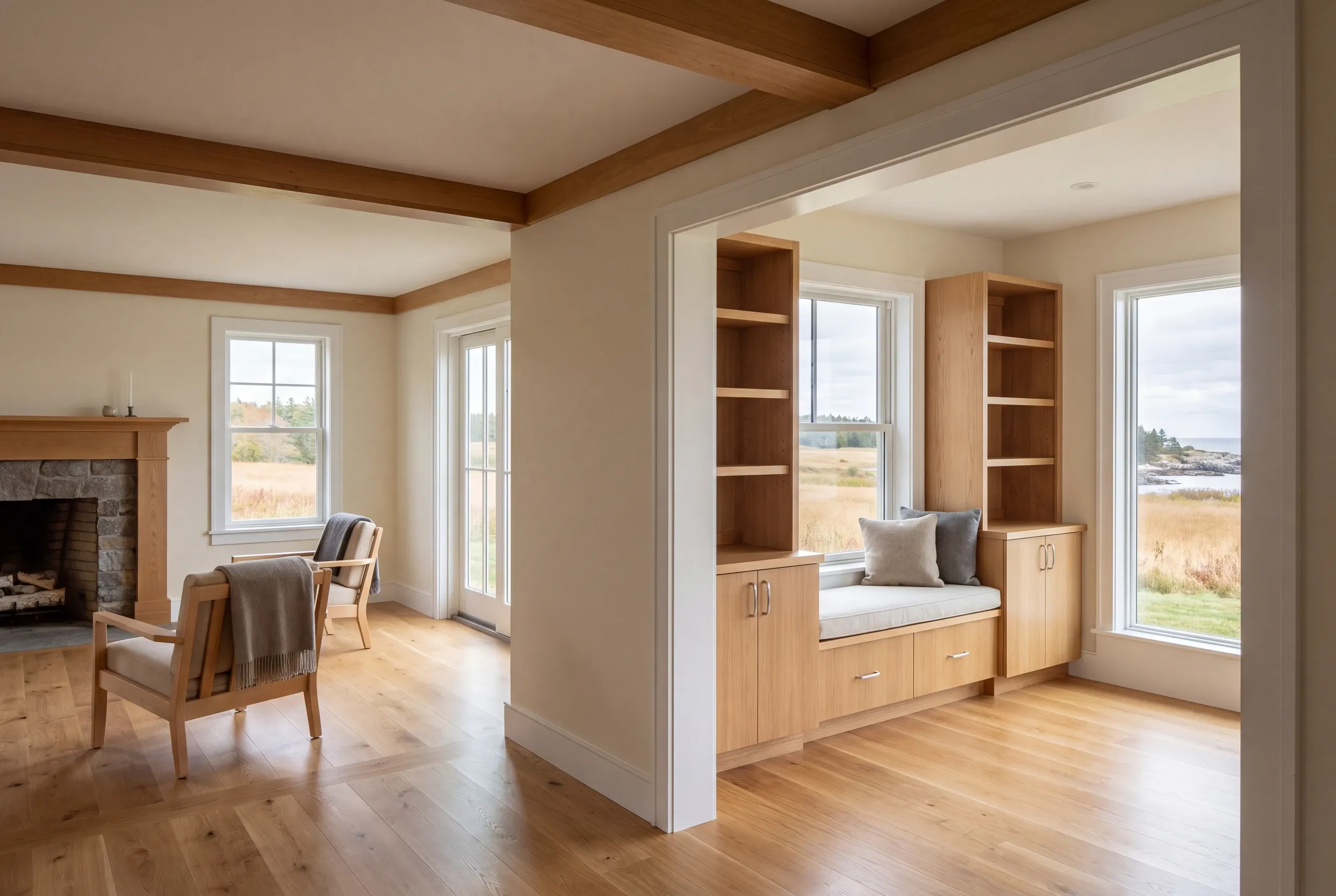 A wide doorway connects a finished living room with a fireplace to an adjoining room featuring a built-in window seat and bookcases.