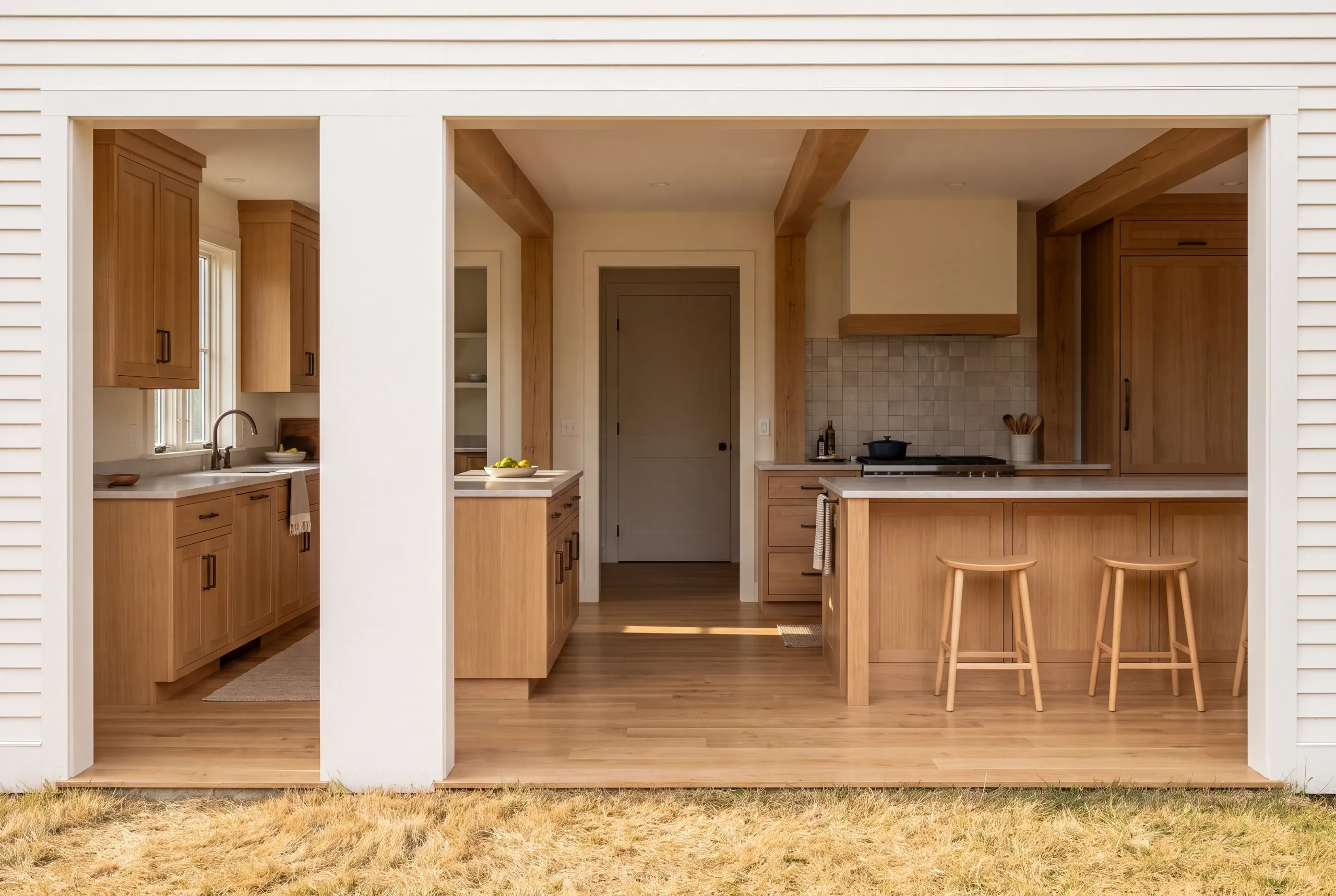 Kitchen remodeling: a kitchen interior featuring oak storage cabinets, pale counters, wood beams, and a clear cooking aisle viewed through large openings.