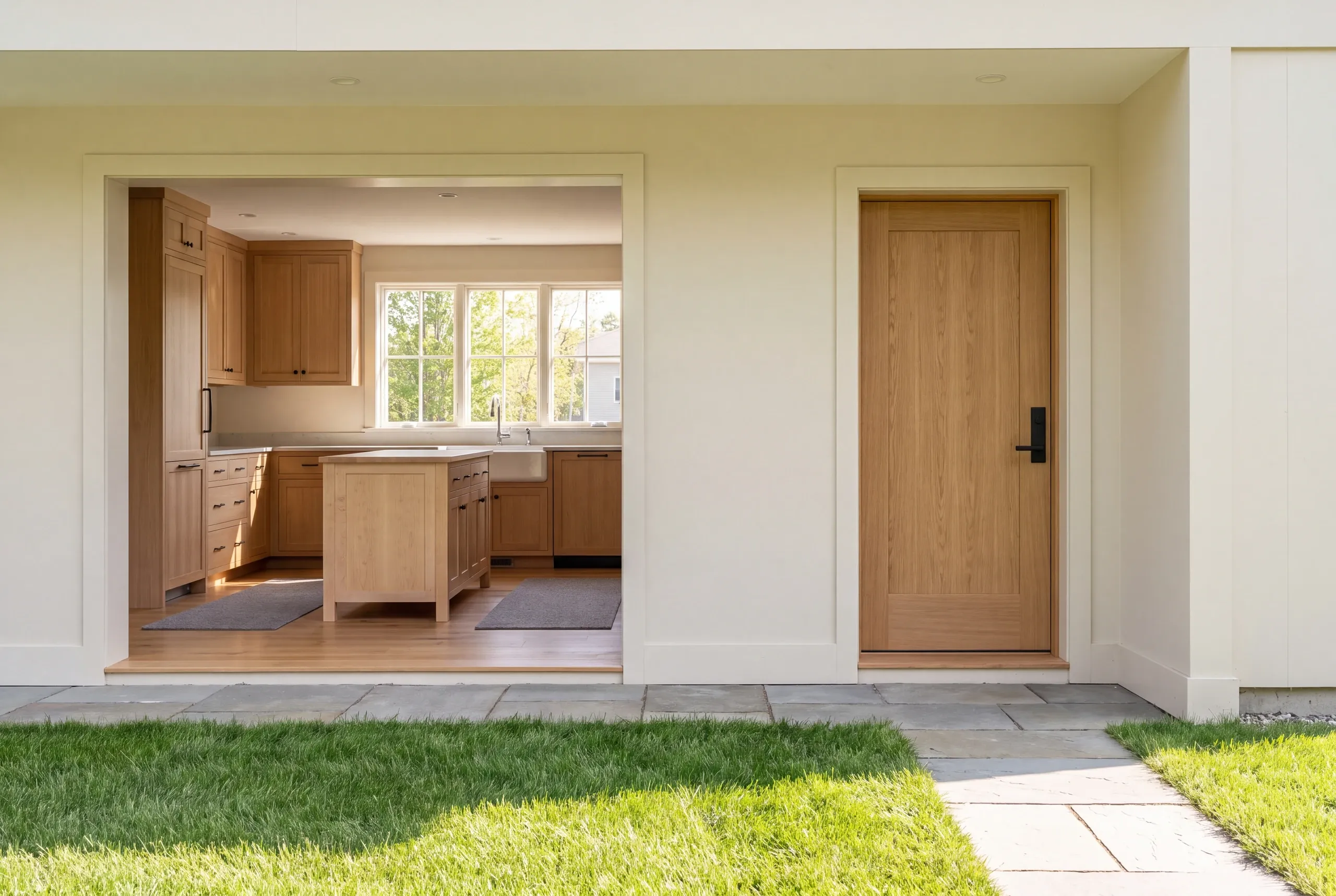 A view of a finished kitchen interior and wooden doorway from an exterior patio.