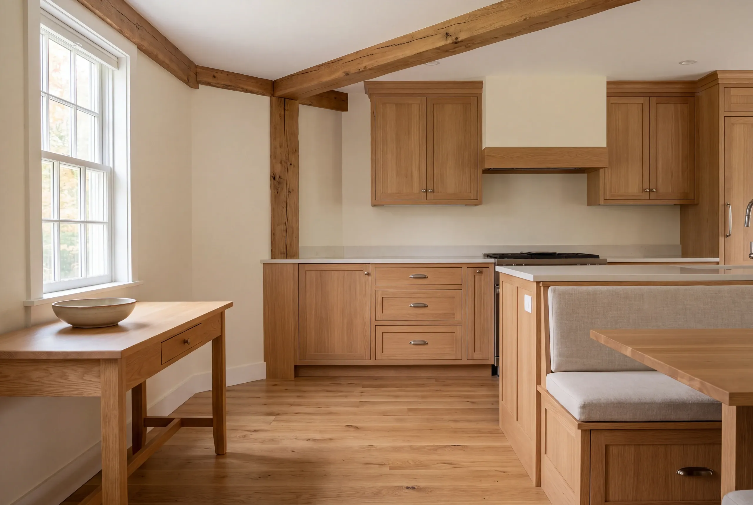 A finished kitchen with wooden cabinetry, exposed beams, a dining table with bench seating, and a window.