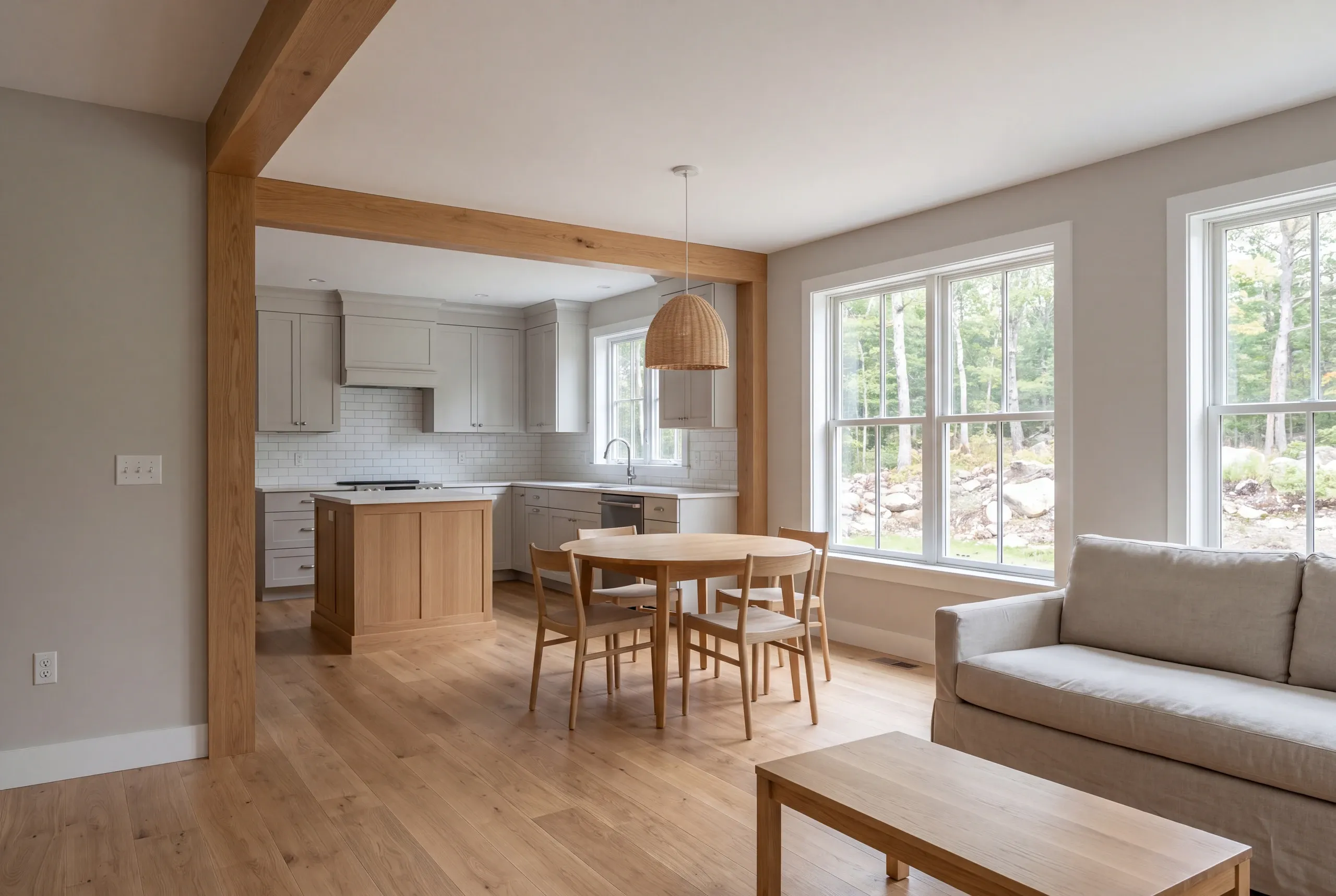 Interior view showing a connected living area, dining space with a round table, and kitchen with light-colored cabinets.