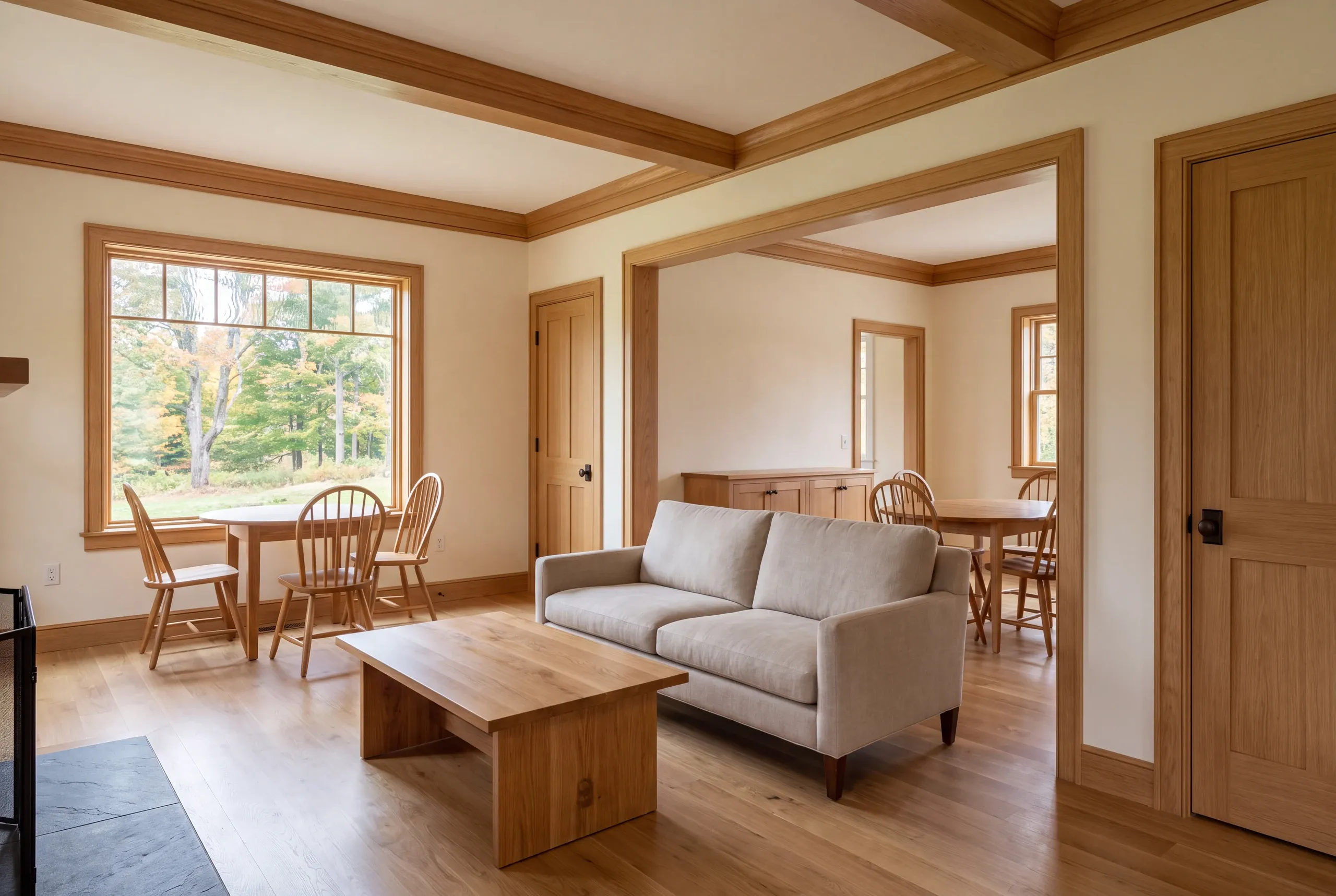 Interior view showing connected living and dining areas with oak trim, wood flooring, and staged furniture.