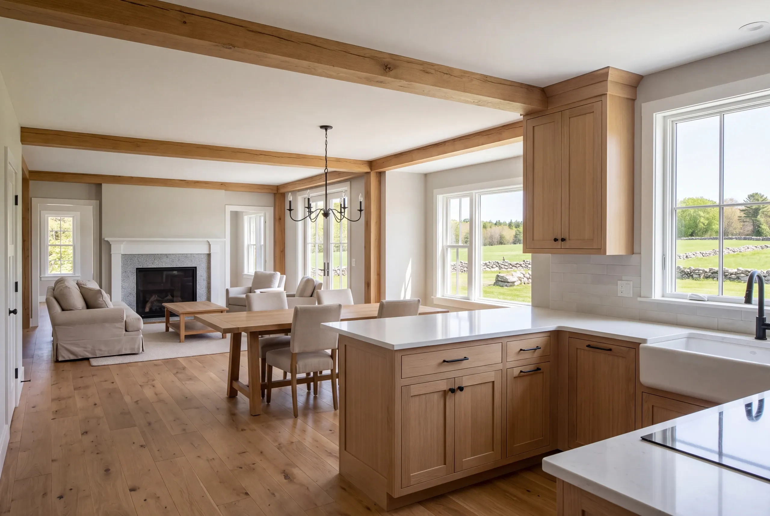 Interior view showing a kitchen with wooden cabinets and island, flowing into a dining area with a wooden table and chairs, and a living area with a fireplace and sofa.