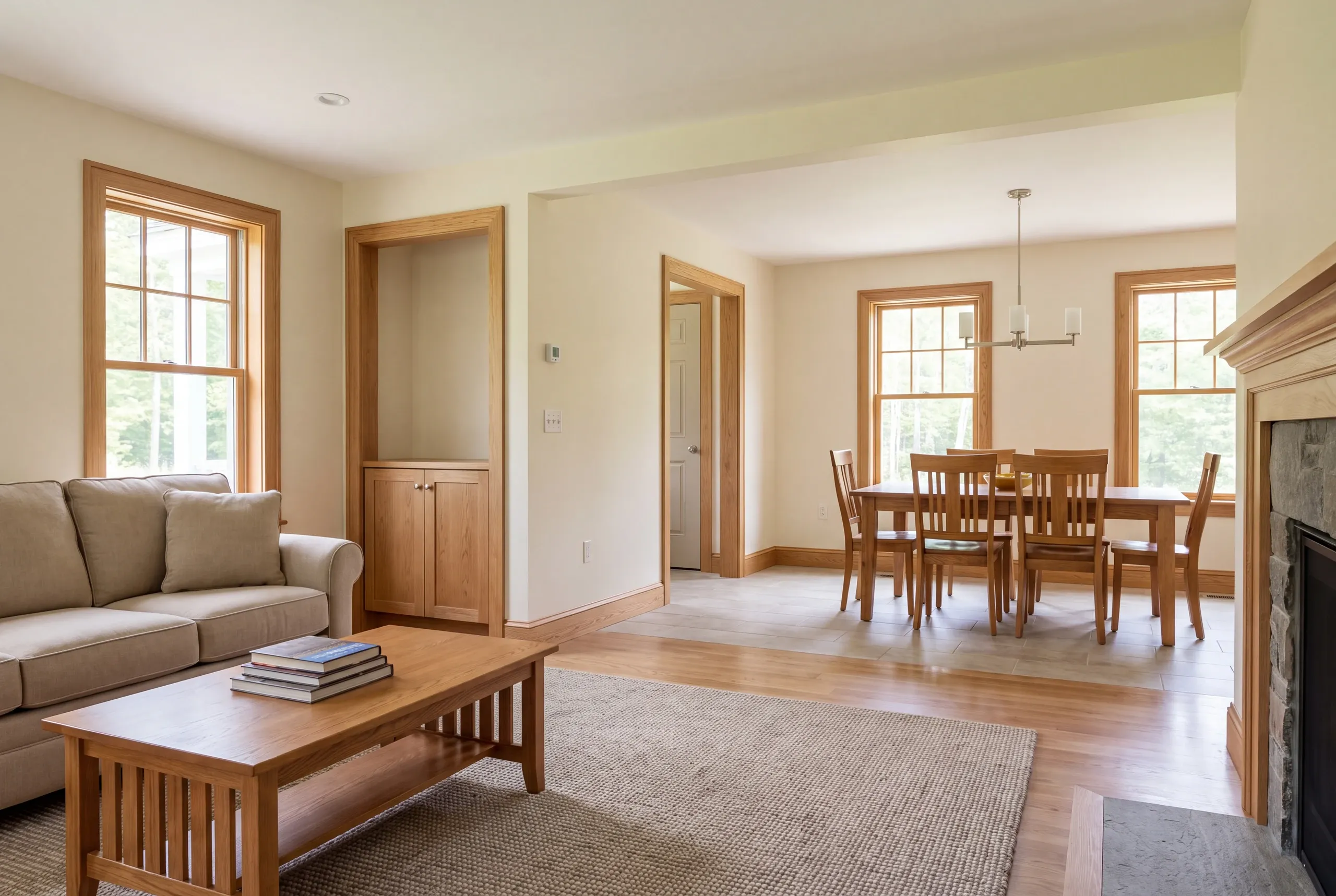 Interior view of connected living and dining rooms featuring oak trim, hardwood floors, and a dining table with chairs.