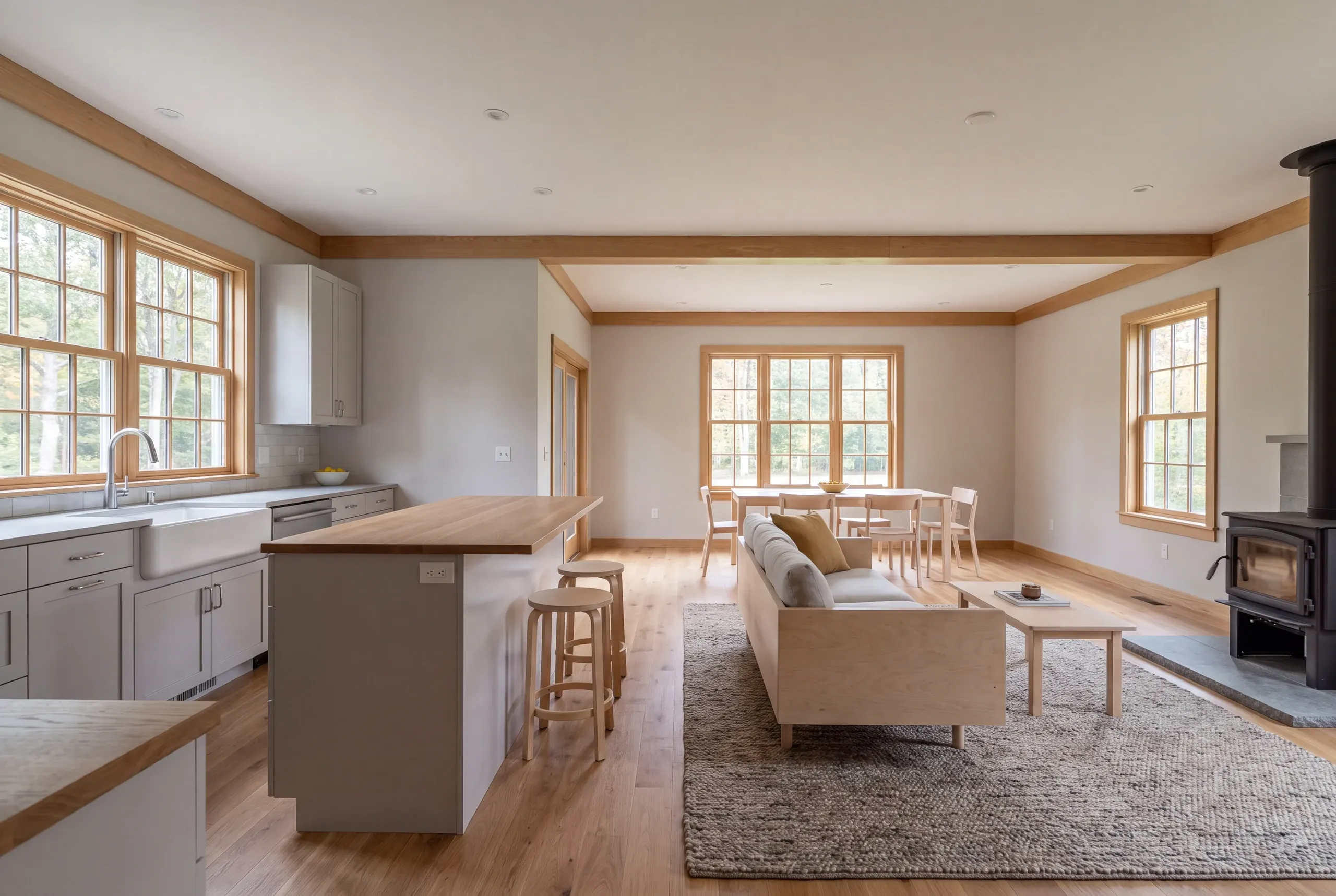 Interior shot showing an open plan kitchen, dining area, and living room with wooden trim and flooring.